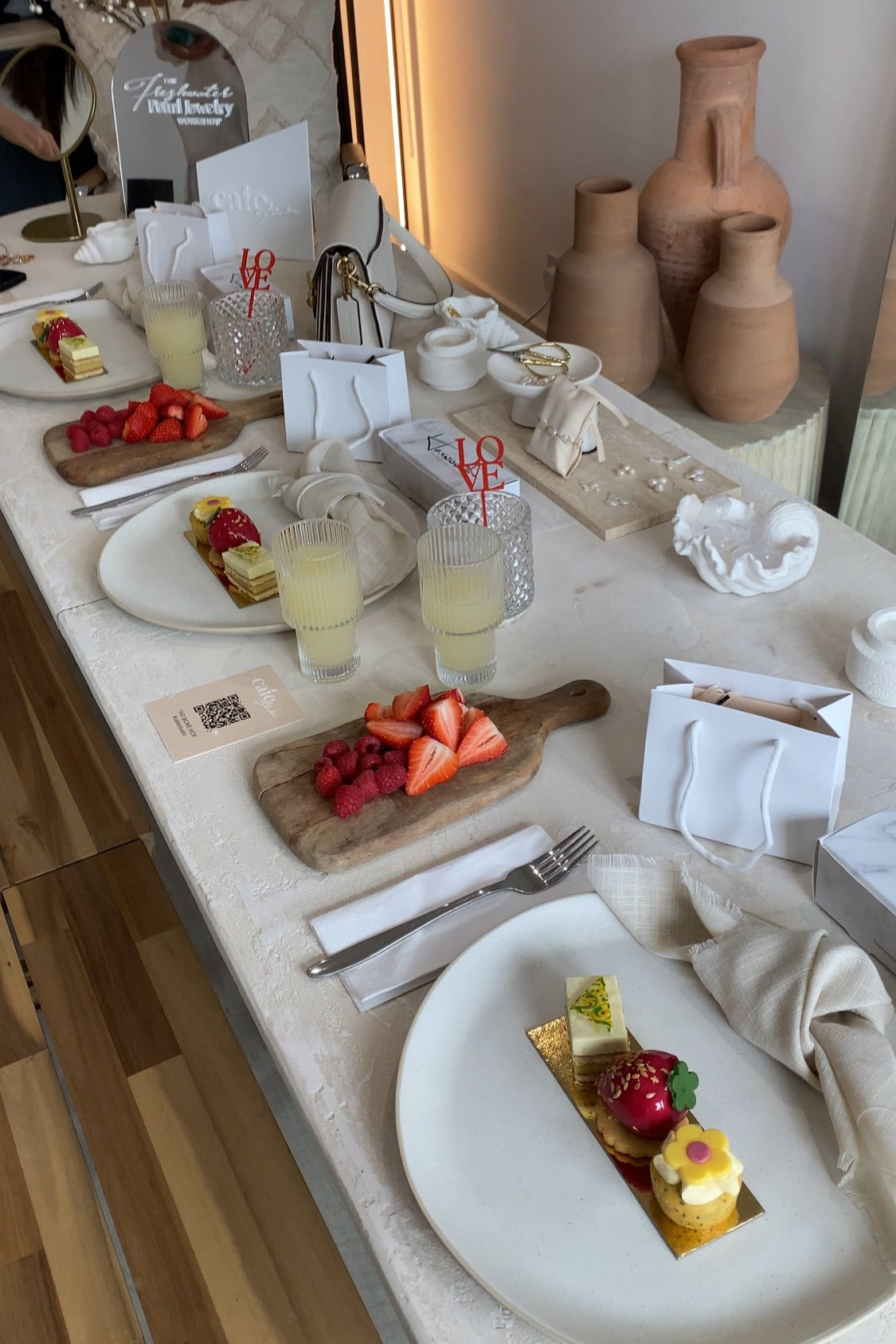 Table setting with plates, glasses, and small desserts on a white tablecloth.